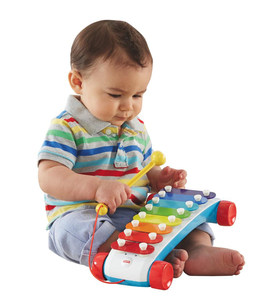 Xylophone classique de Fisher Price. 8 notes de couleur, un octave. Le bâton est attaché et le xylophone a des roues. 18 mois et +. Bébé assis joue avec le xylophone